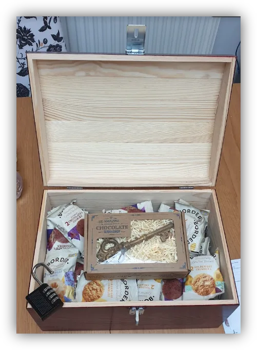 An open wooden escape-room chest containing clues and padlocks